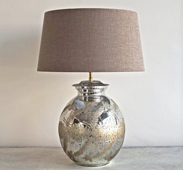 a silver mercury glass vase with a lamp on a table