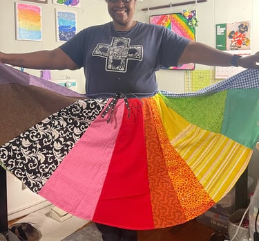 a black woman holding a rainbow - colored skirt