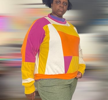 a black woman in a colorblock sweater and green pants