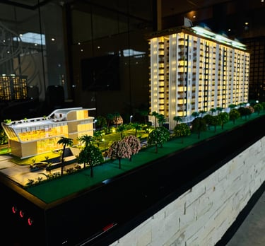 Illuminated architectural scale model of a modern luxury high-rise apartment building and clubhouse.