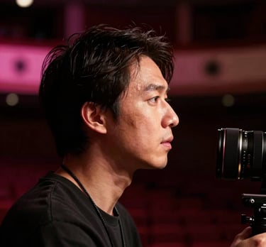 Close-up profile of a professional lighting designer at work in a dark North American / US theater, with subtle pink lighting in the background.