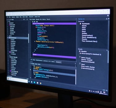 A high-resolution 4K monitor displaying a complex code editor with syntax highlighting in electric blue and purple. North American / US tech environment.