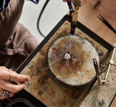 Joyero usando un soplete  para soldar un anillo de plata hecho a mano sobre un bloque de soldadura