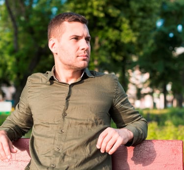 Un homme pensif assis sur un banc dans un parc arboré