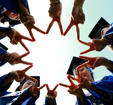 Group of graduates in blue gowns and caps forming a star shape with their fingers while celebrating 
