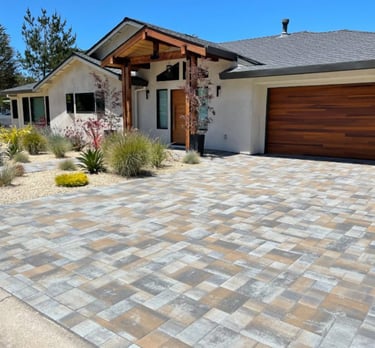 a driveway with random color pavers and a desert plant landscape
