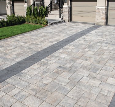 a brick paver driveway with earthy colors and dark center and border