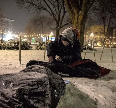 Man sitting in City Hall Park with his belongings in the snow.