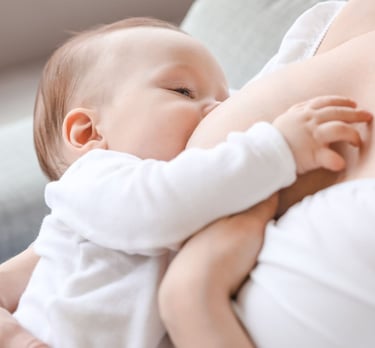 IBCLC žindymo konsultantė Eglė Gurčinė padeda mamai žindyti naujagimį.