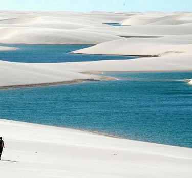 two people walking on a beach with a blue sky