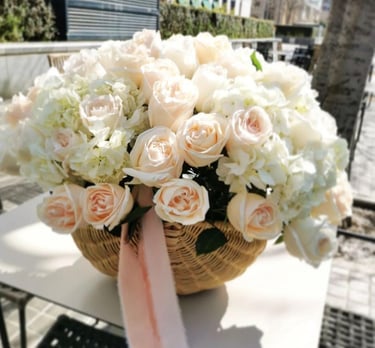 Elegant floral arrangement of peach roses and white hydrangeas in a wicker basket.