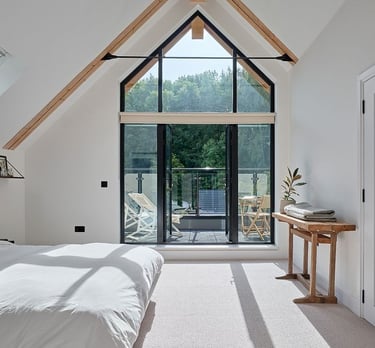Loft conversions - a bedroom with a large window and a bed