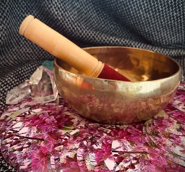 A singing bowl next to crystals and an oracle deck