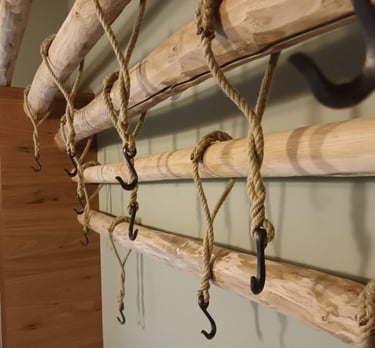 geschmiedete Kleiderhaken an Tauen an einer Holzgarderobe