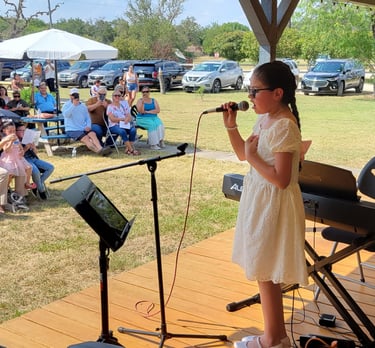 a young girl in a yellow dress is singing into a microphone 