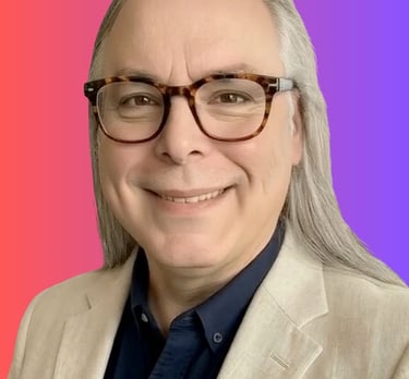 Smiling man with long grey hair and tortoiseshell glasses in a tan blazer against a pink and purple background.