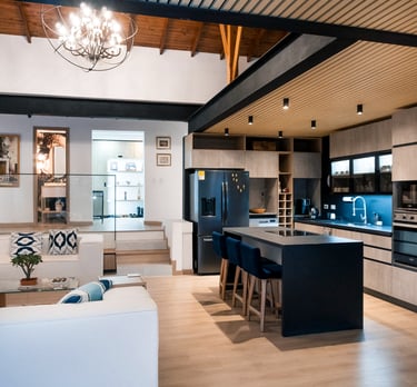 Cocina moderna de concepto abierto, isla central negra, iluminación empotrada y acabados en madera
