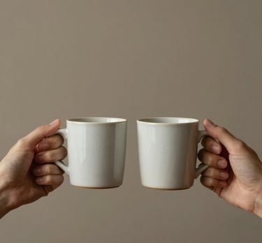 Minimalist shot of two hands holding warm ceramic mugs, representing the warmth of human contact versus digital screens.