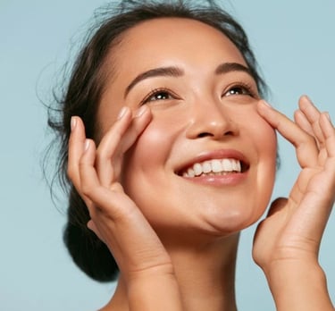 Mujer sonriente con piel radiante aplicando crema para los ojos en su rutina de hidratación facial.
