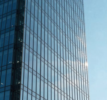 A minimalist shot of a modern glass skyscraper reflecting a bright blue sky, symbolizing clarity and growth. North American / Global Financial Market.