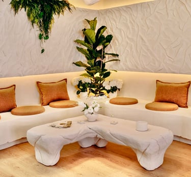 Modern lounge area featuring white tufted club chairs, a blue sofa, and red walls.