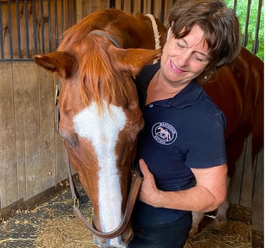 Calm, relaxed horse with eyes closed, resting his head on Danna's shoulder during bodywork session.