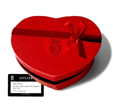 Red heart-shaped gift box with a satin bow and a personalized Atelier note.
