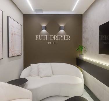 Ambiente interno da Ruti Dreyër Clinic com logo na parede e sofá, destacando a sala de espera.