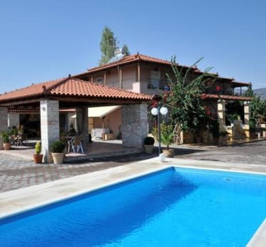 Luxurious villa with a clear blue swimming pool and a shaded outdoor seating area, perfect for a relaxing vacation.