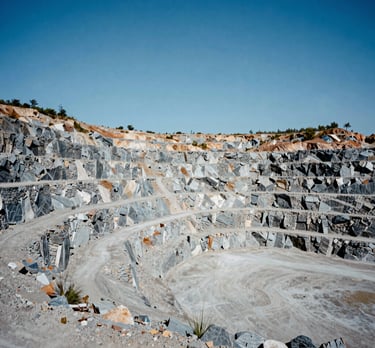 A wide-angle shot of a North American quarry with structured terraces of gray stone under a clear blue sky.