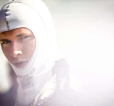 Professional race car driver wearing a white Sparco fireproof balaclava and racing suit.