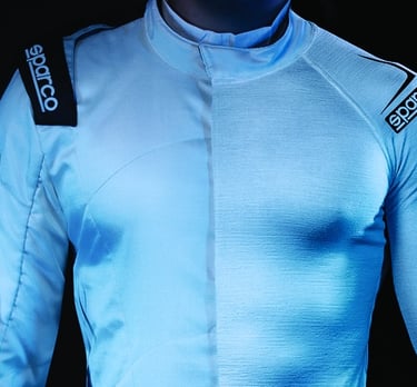 A driver wearing a white Sparco fire-resistant racing suit with shoulder logos.