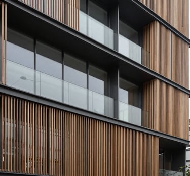 Clean, architectural shot of a modern office building with traditional Japanese wooden slats and large windows. Muted charcoal and light gray colors. Hispanic / Japanese-inspired style.