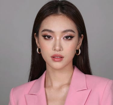 Retrato de una mujer con delineador de ojos alado y maquillaje rosa suave con una chaqueta rosa.