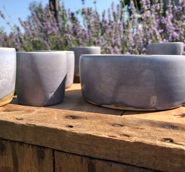 Plusieurs poterie de couleur lavande devant des lavandes en fleur