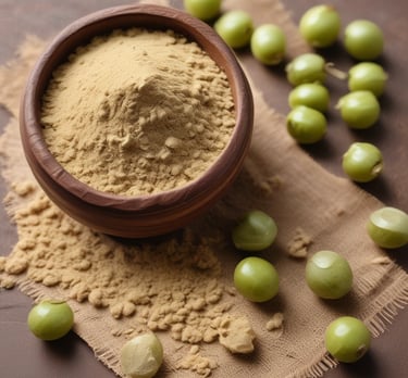 Amla powder displayed in a small glass jar with fresh amla fruits and green leaves around it.