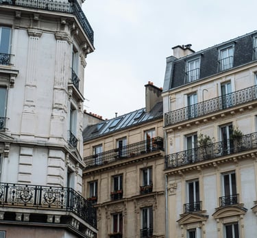 Immeubles haussmanniens avec balcons en fer forgé sous un ciel clair, architecture typique de Paris