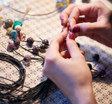 manos poniendo piedras sobre un hilo para realizar una pulsera