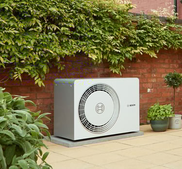 Bosch air source heat pump installed in a residential garden against a brick wall for energy efficiency.
