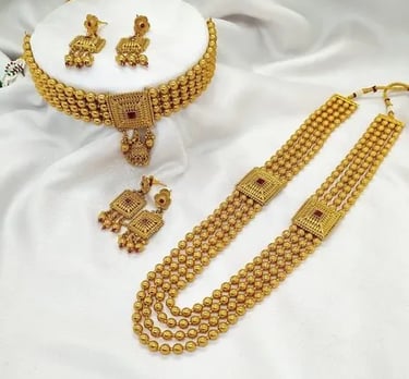 Elegant gold choker and long layered necklace set with matching earrings on white fabric.