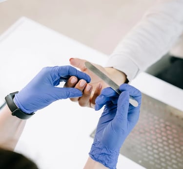 A manicurist with gloves fixing a customer's nail.