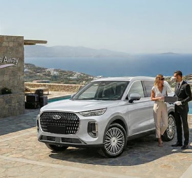 Luxury white Chery SUV parked at a seaside villa with a chauffeur assisting a traveler.