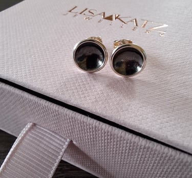 Handmade silver stud earrings with dark circular inserts on a pink Lisa Katz Jewellery box.