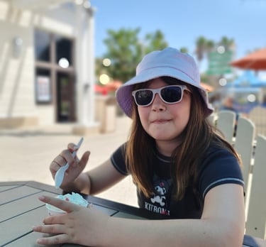 a woman in a hat and sunglasses sitting at a table
