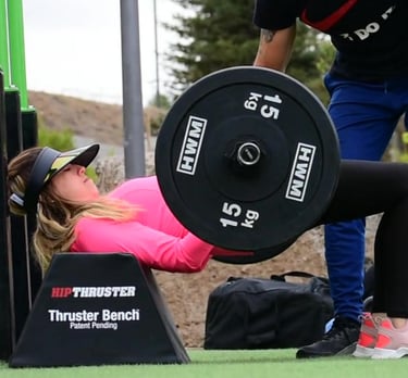 Entrenador ayudando a alumna para hacer hip thrust