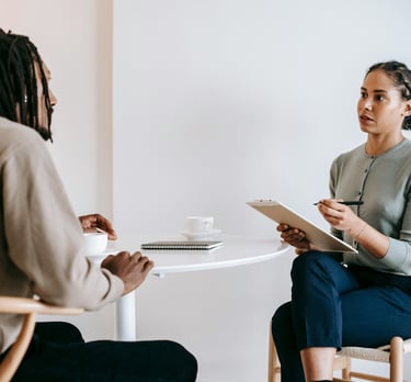 Une femme assise à une table et un homme sur une chaise en train de discuter