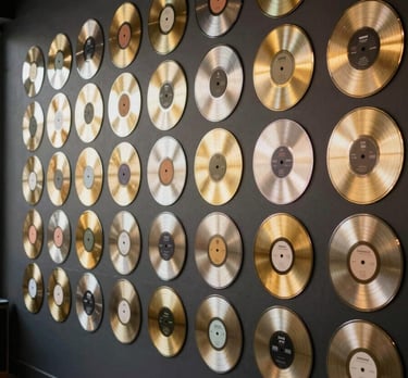 A wall covered in gold and platinum records in a stylish, dark charcoal room, symbolizing professional success and high standards.