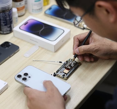A friendly technician carefully repairing a smartphone at a bright, modern shop counter.