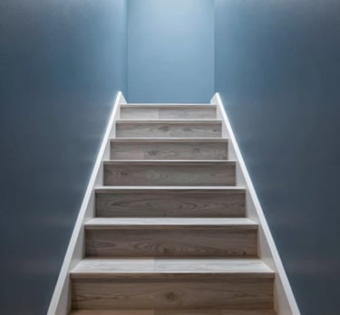 Clean, minimalist shot of a modern staircase in a North American home, featuring slate blue walls and light gray wood steps.