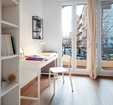 "Un escritorio con otro escritorio y una silla frente a una ventana."